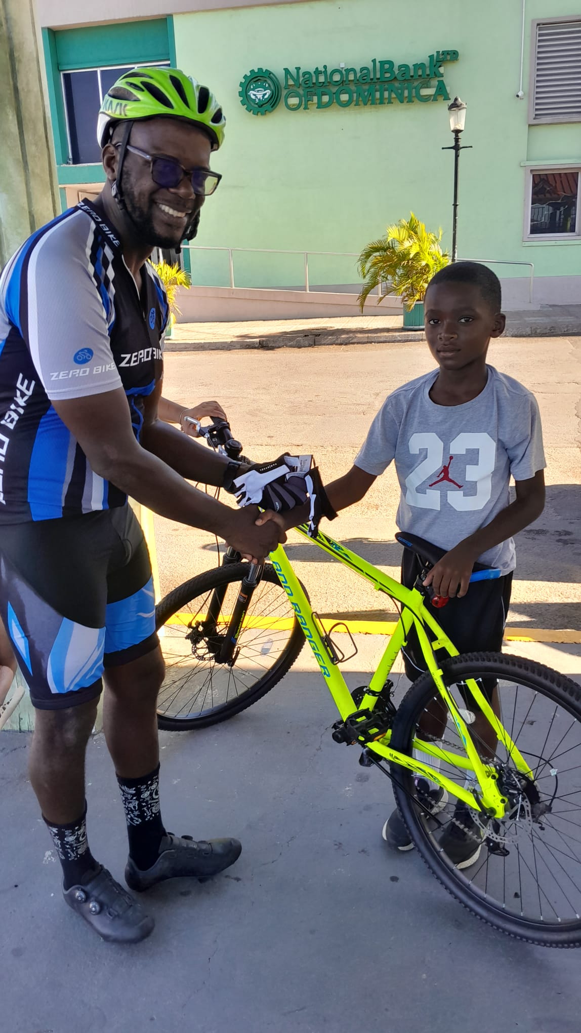 Ronald Charles, president of the Dominica Cycling Association, interacts with a young cyclist prior to the association's Fun Ride in Roseau to promote safety among cyclists on November 25th, 2023.
